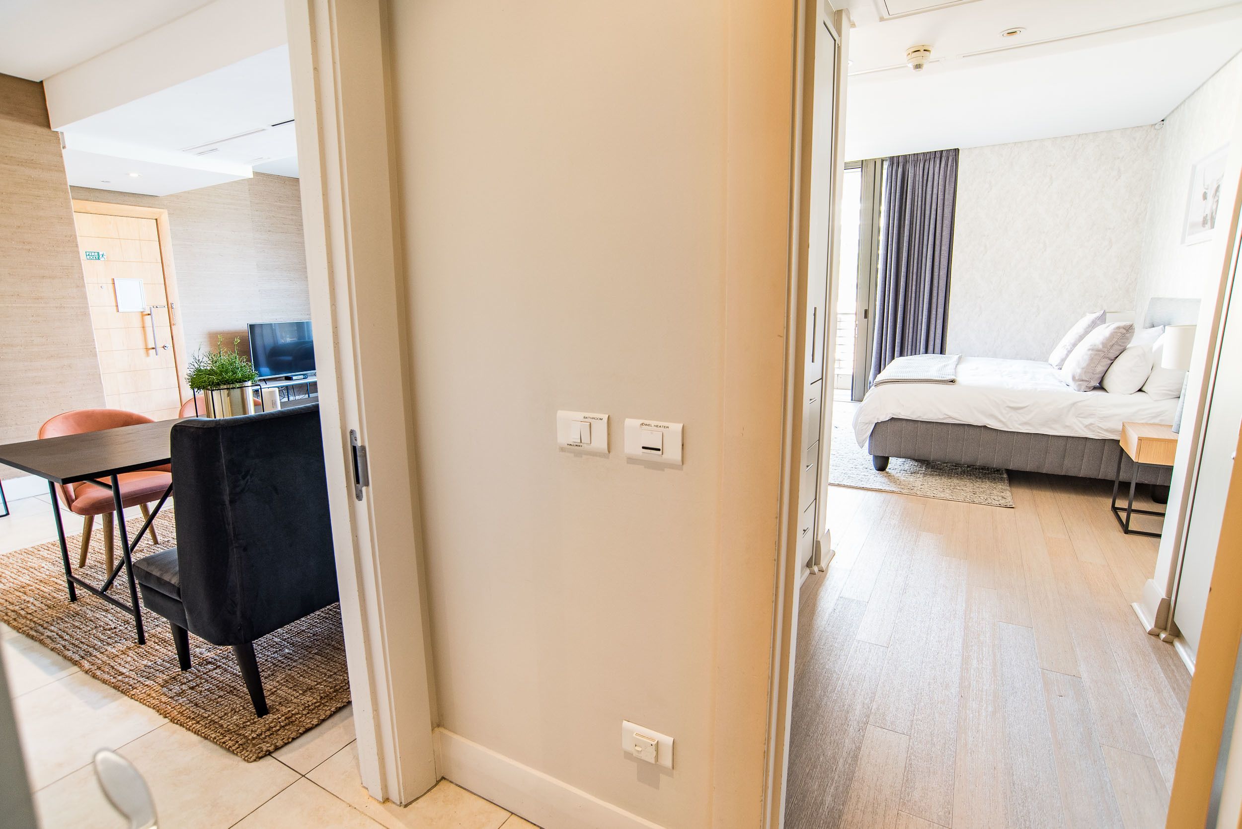 A hotel room with a bed, bedside table, and a view of the hallway.