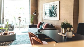 En moderne stue med sofa, stole, et sofabord og potteplanter.