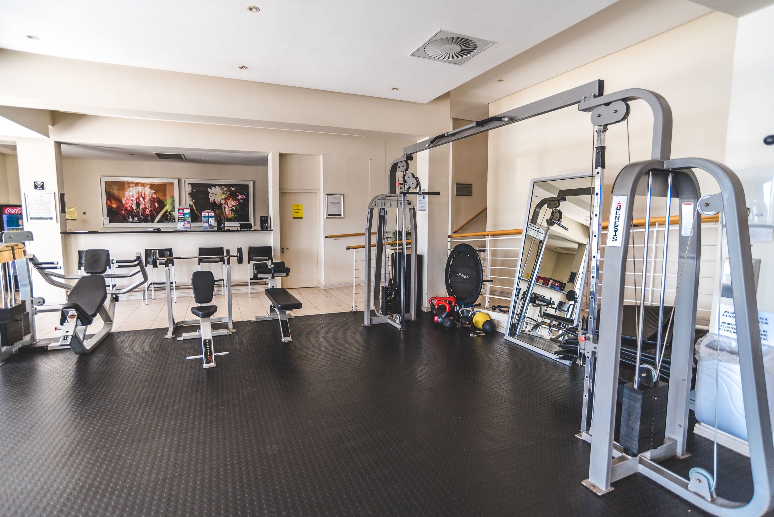 A gym with various exercise equipment, a bench, and a mirror.