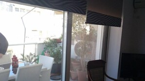 A room with a sliding glass door leading to a balcony with outdoor furniture and potted plants. - Luxury Flat with Amazing Lycabetus View (Athens)