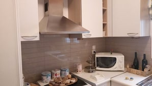 A kitchen with white cabinets, a microwave, a toaster, and a small countertop with jars and bottles. - Luxury Flat with Amazing Lycabetus View (Athens)