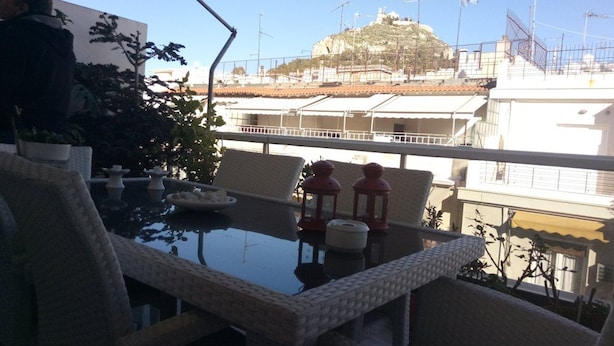 A terrace with a table, chairs, and potted plants. - Luxury Flat with Amazing Lycabetus View (Athens)