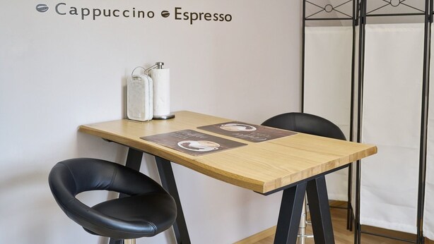 A small table with two chairs, a menu, and a coffee machine. - Ferienwohnungen Kampe (Stemwede)