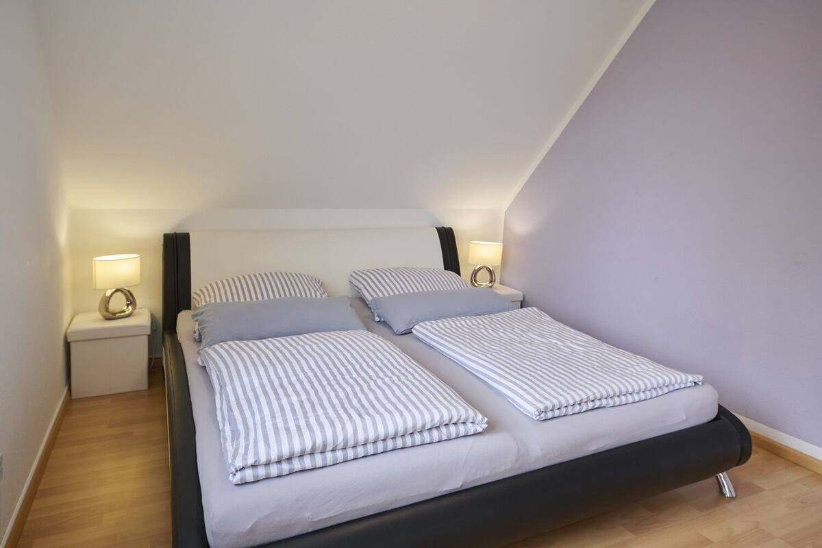 Un dormitorio moderno con una cama, dos mesitas de noche y un buró.