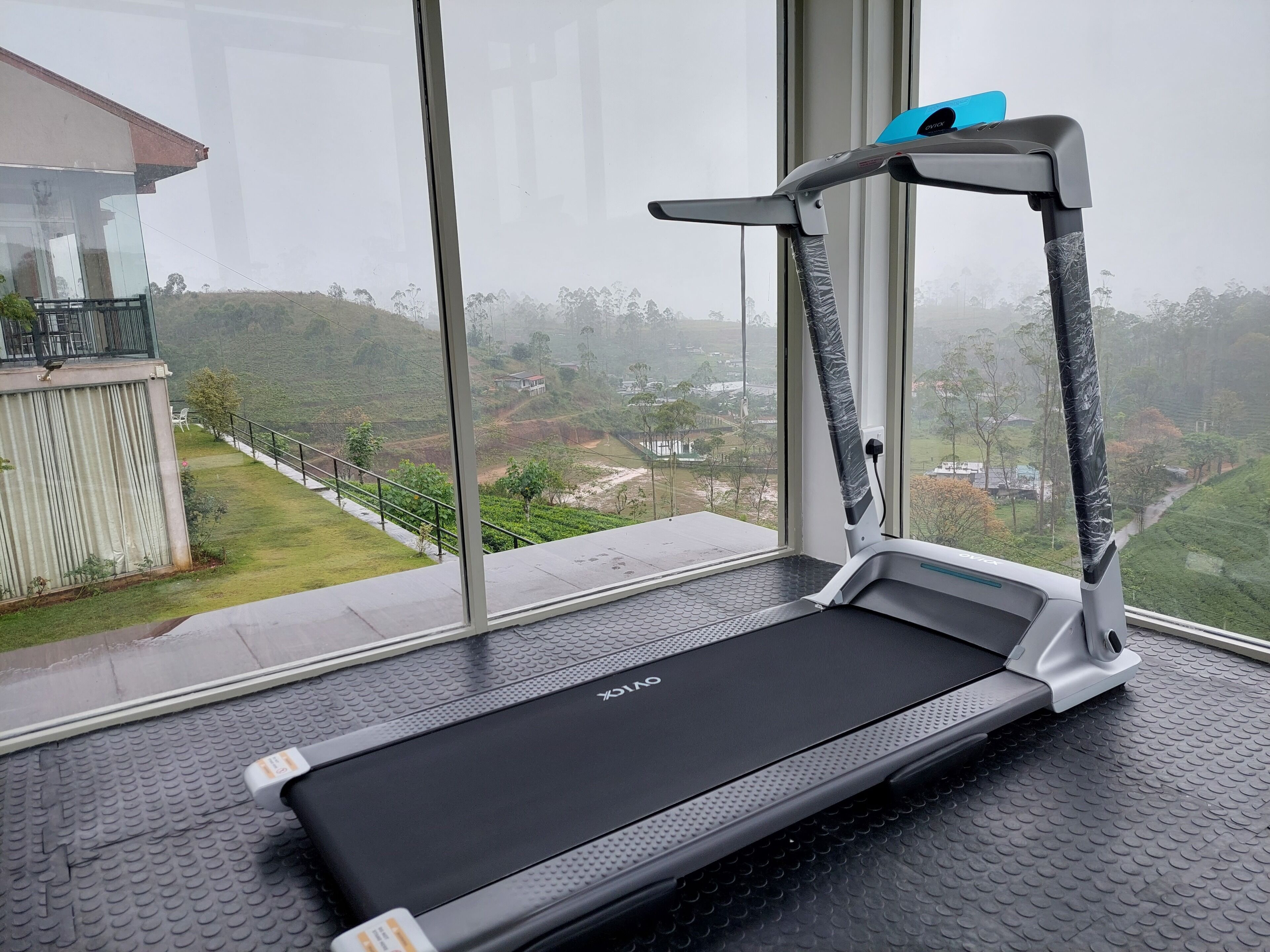 Una cinta de correr en una habitación con ventanas amplias que dan a un paisaje montañoso.