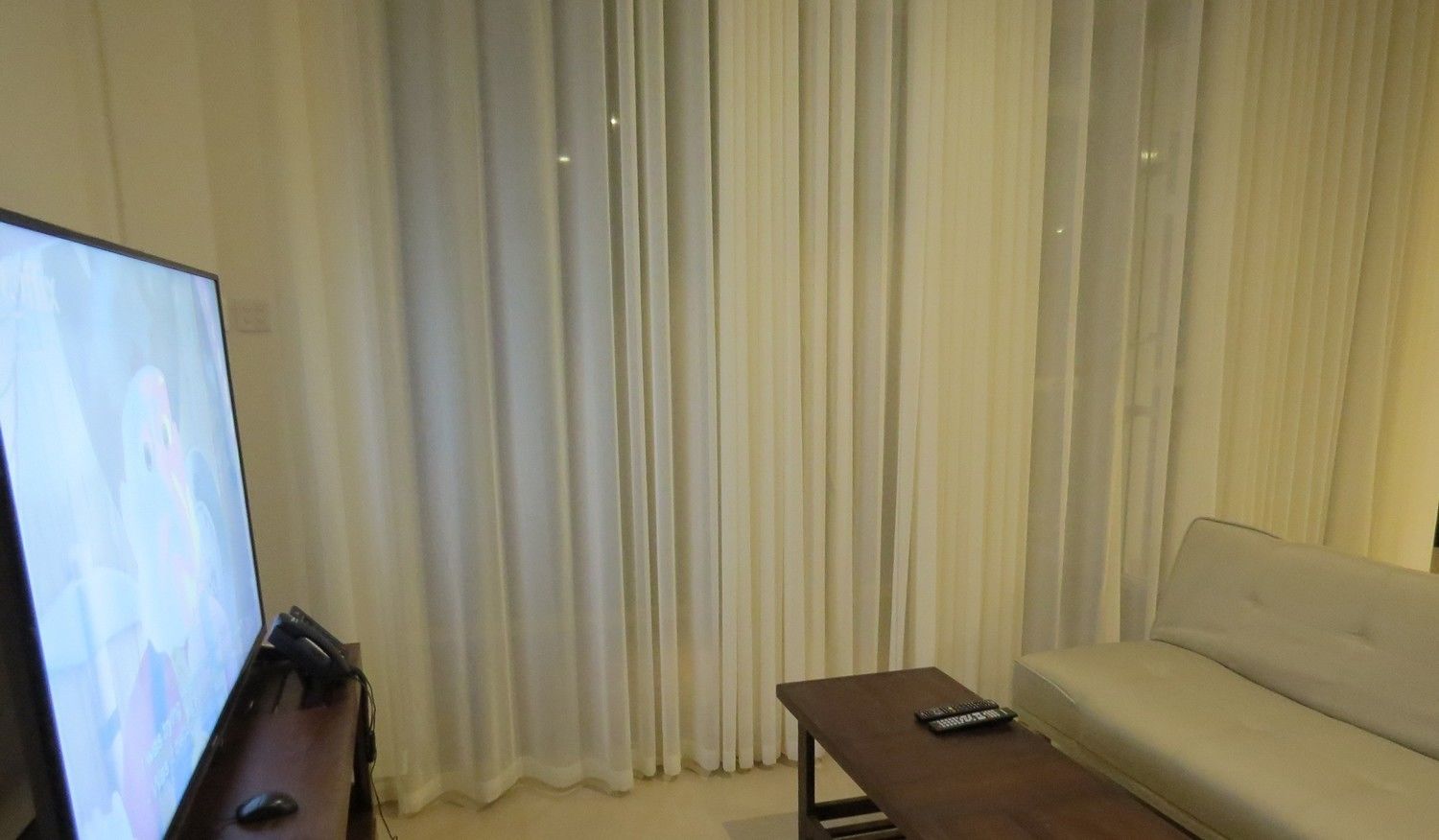 Una sala de estar con un televisor de pantalla plana sobre un mueble bajo, un sofá y una mesa de centro.