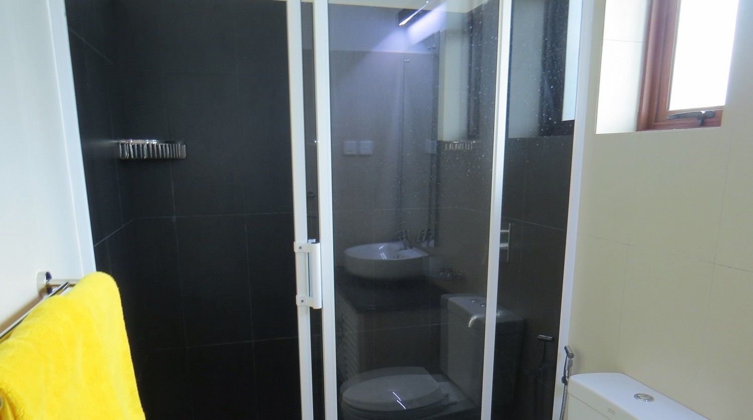Une salle de bain avec une douche à parois de verre, des toilettes et un lavabo.