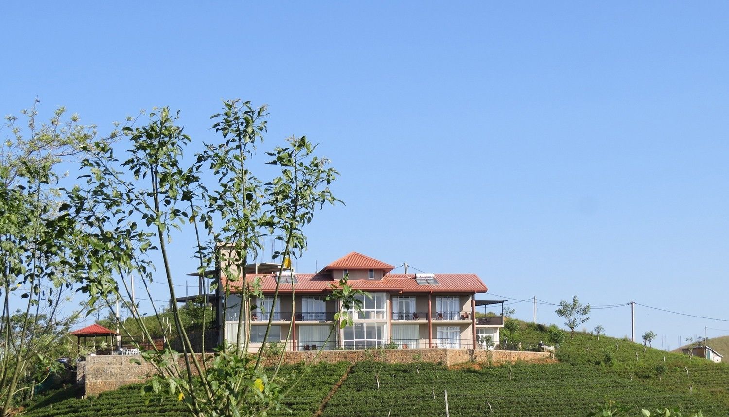 A two-story building with a red roof, surrounded by a green landscape and a clear blue sky.