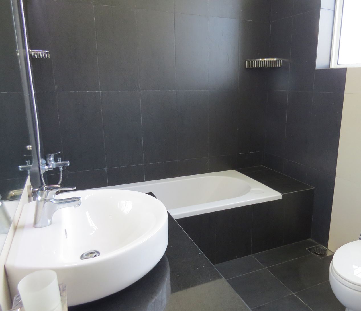 Een moderne badkamer met een wit wastafel, een badkuip en een toilet.