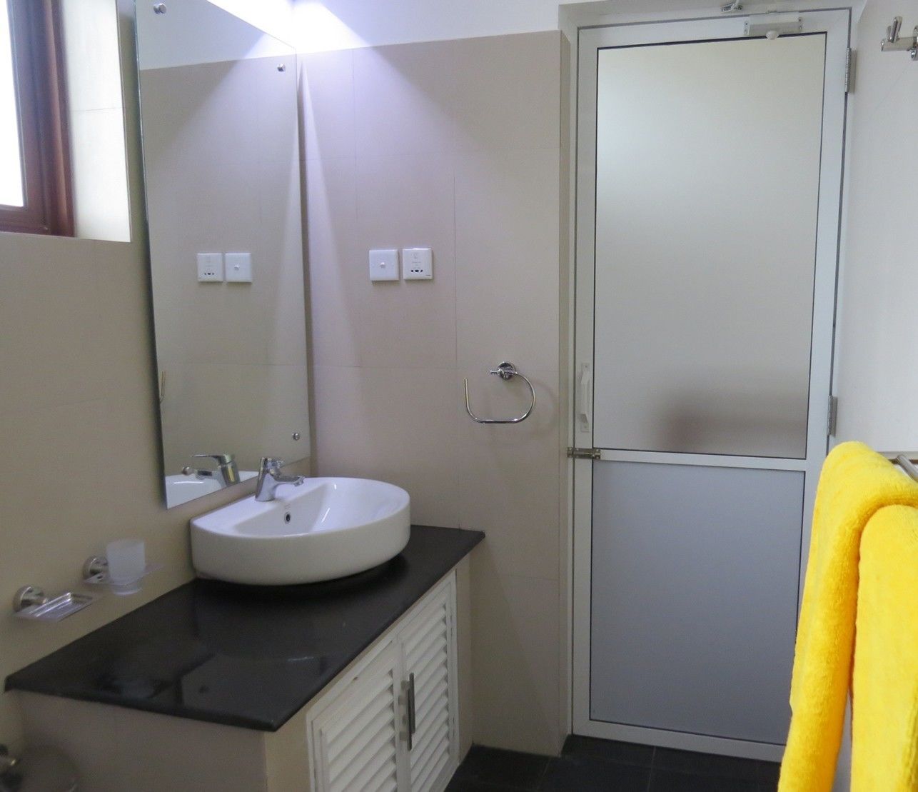 A bathroom with a white sink, a mirror, a towel rack, and a door.