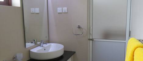 A bathroom with a white sink, a mirror, a towel rack, and a door.
