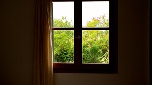 Una ventana con vista a follaje y una cortina entreabierta.