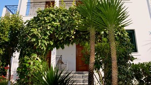 Un edificio blanco con un balcón, una puerta de madera y una escalera que lleva a la entrada.