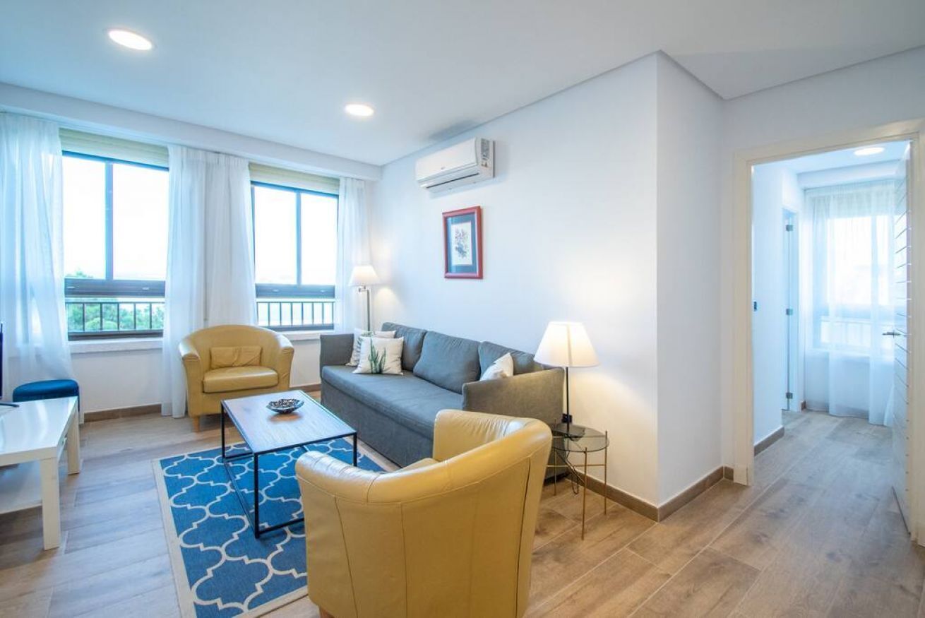 A modern living room with a sofa, armchairs, a coffee table, and a lamp.