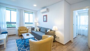 A modern living room with a sofa, armchairs, a coffee table, and a lamp. - Apartamento Albatro´s suite (Cádiz)