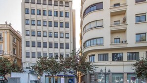 A modern building with a grid of windows, a curved facade, and a flat roof. - Apartamento Albatro´s suite (Cádiz)