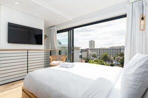 A modern hotel room with a large bed, a flat-screen TV mounted on the wall, and a balcony with a city view. - TenonQ C14 (Cape Town)