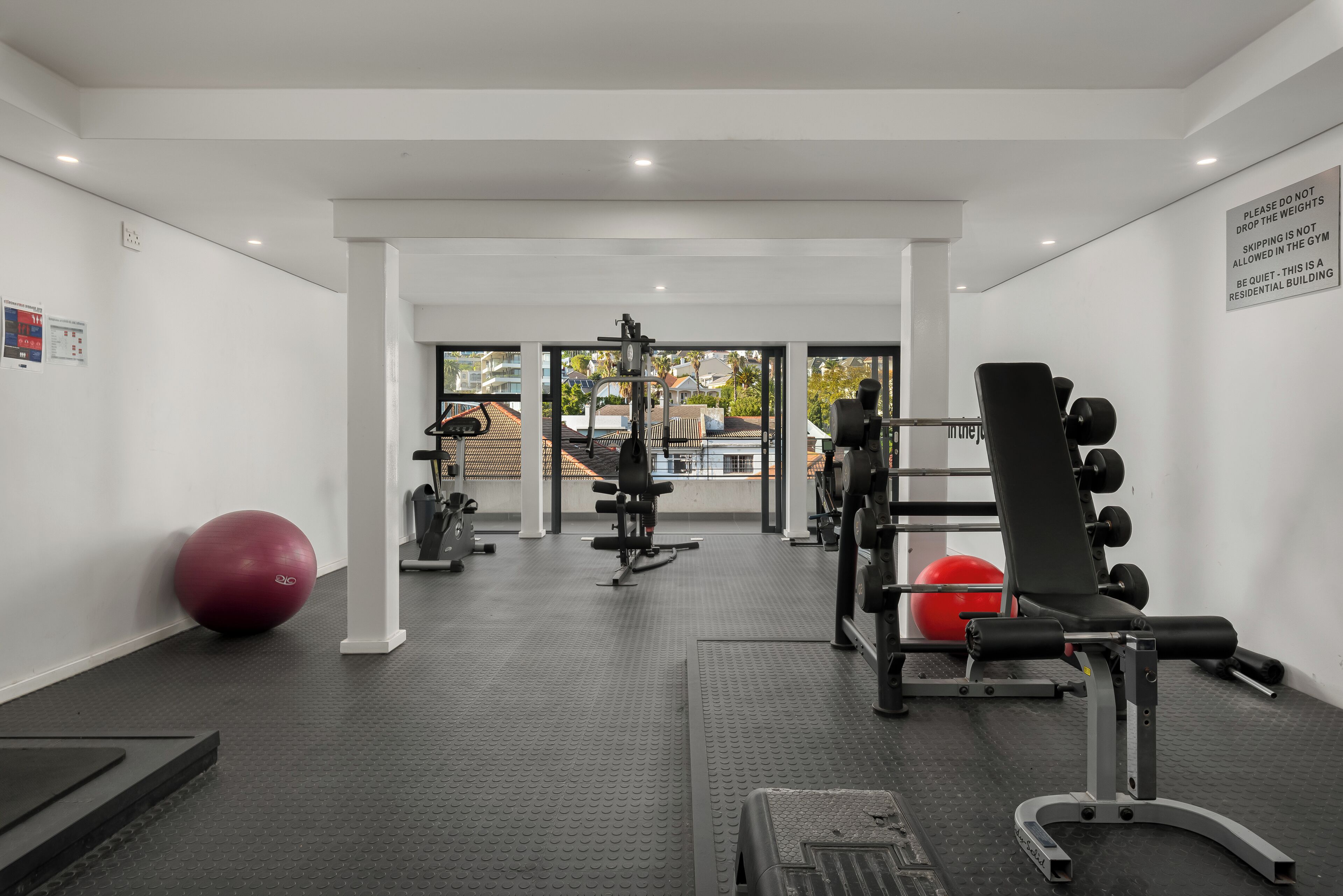 A gym with exercise equipment, a red exercise ball, and a black weight bench.