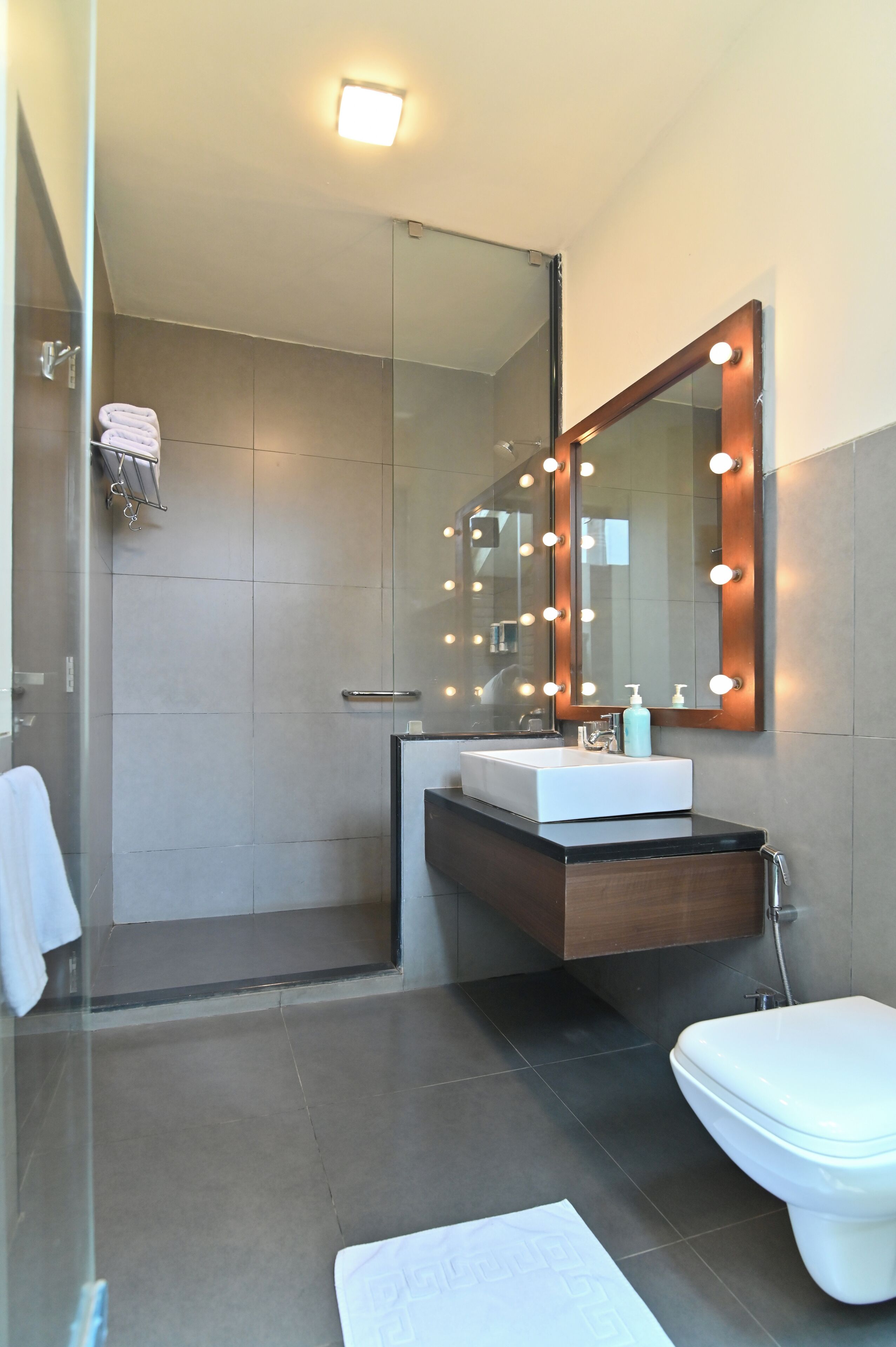 Un baño moderno con cabina de ducha de vidrio, tocador con espejo y retrete.