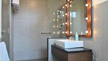 Un baño moderno con cabina de ducha de vidrio, tocador con espejo y retrete.