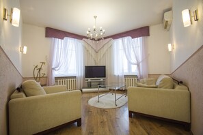 Relax in this inviting living room with a large flat-screen TV, two comfortable armchairs, and a glass coffee table.
