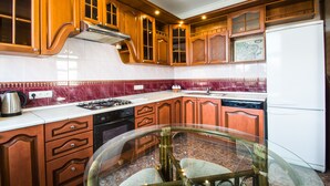 A kitchen with wooden cabinets, a glass table, and a white refrigerator. - iRent.by Nemiga (Minsk)