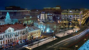 A nighttime cityscape with illuminated buildings and a snow-covered street. - iRent.by Nemiga (Minsk)