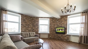 A living room with a brick wall, a sofa, a coffee table, and a TV. - iRent.by Nemiga (Minsk)