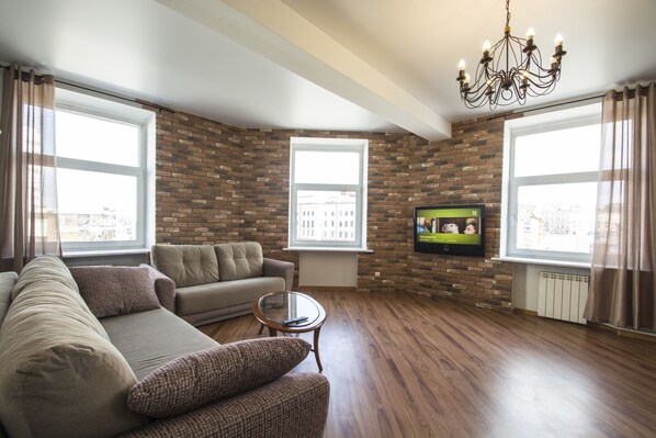 A living room with a brick wall, a sofa, a coffee table, and a TV. - iRent.by Nemiga (Minsk)