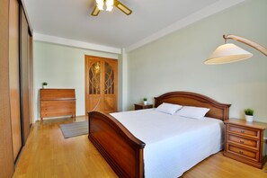A bedroom with a wooden bed, a nightstand, a dresser, and a ceiling fan. - iRent.by Nemiga (Minsk)