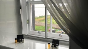 Una habitación con ventana que da a un área verde. Hay tres botellas en el alféizar.
