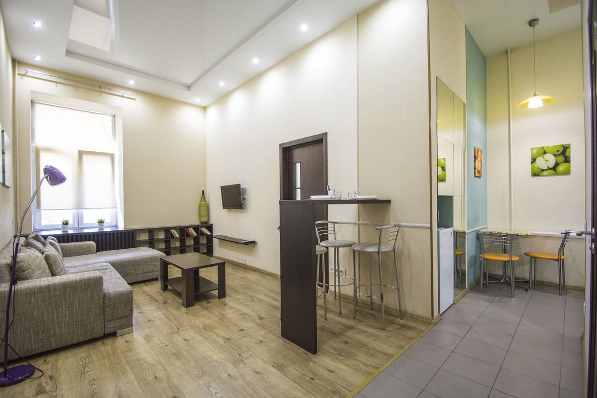 Una sala de estar moderna con un sofá, una mesa de centro y una pequeña zona de bar con taburetes.