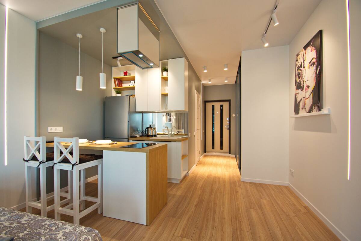 Una cocina moderna con armarios blancos, una isla central e iluminación colgante.