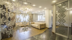 Ein modernes Interieur mit einem beigen Sofa, einer Kristallleuchter und einer Wand mit Muster.