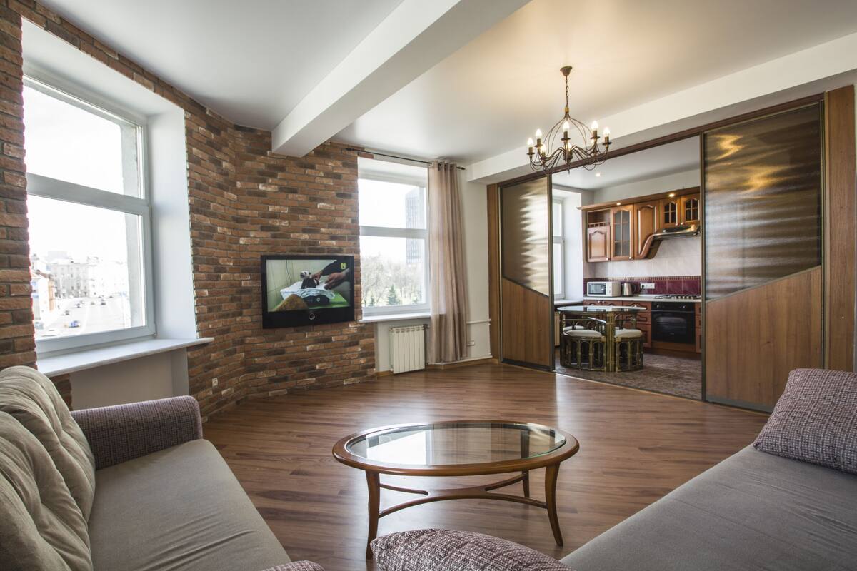 Una sala de estar moderna con pared de ladrillo, una mesa de centro de vidrio y un sofá.