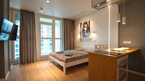 Ein modernes Schlafzimmer mit Bett, Schreibtisch, Fernseher und einem Fenster mit Vorhängen.