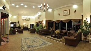A spacious lobby with a central seating area, a glass elevator, and a chandelier. - Seaview Suite Hotel (Kusadasi)