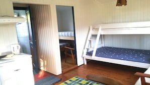 Ein Zimmer mit einem Etagenbett, einem Schreibtisch mit Wasserkocher, einem Stuhl und einem farbenfrohen Teppich.
