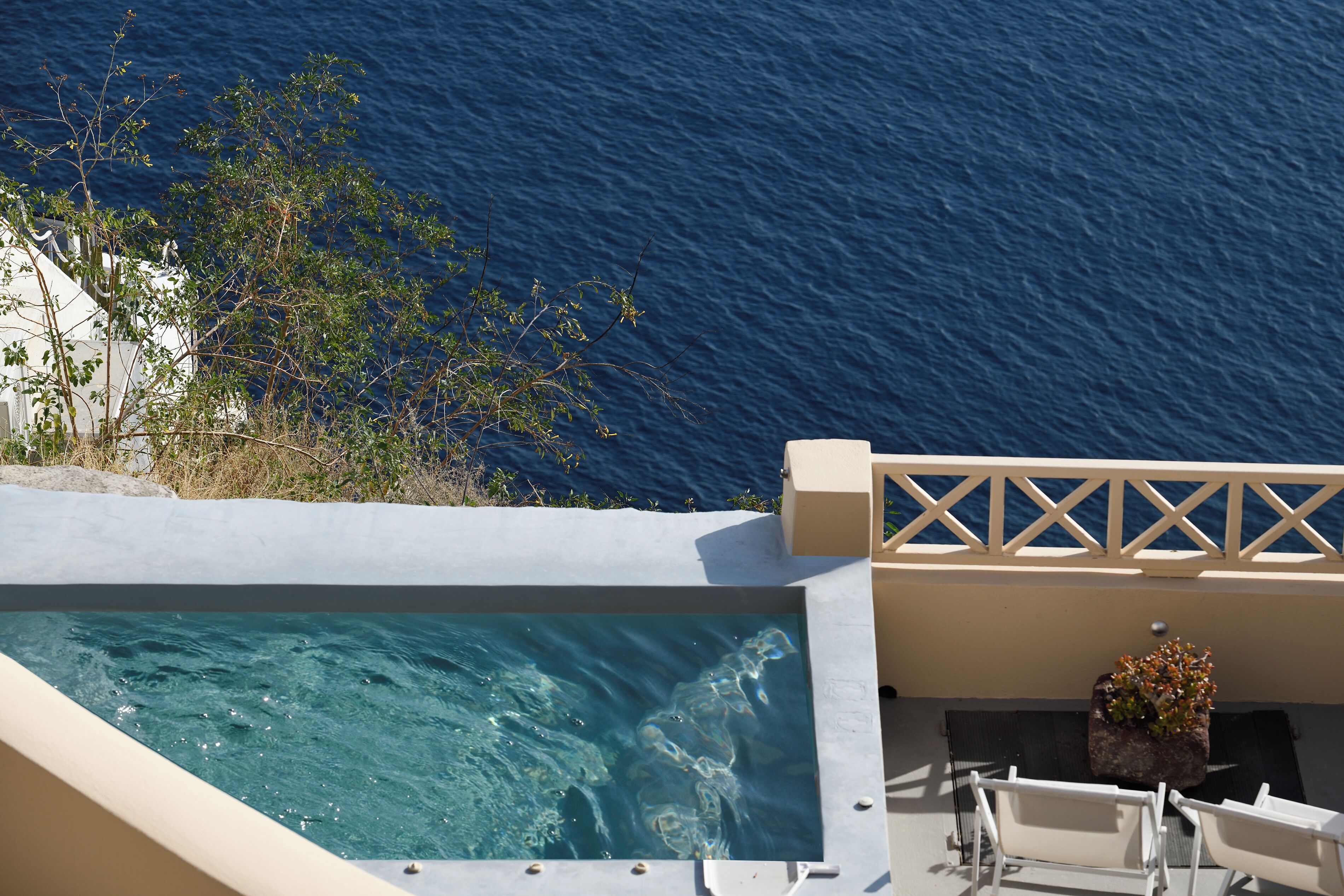 A pool with clear blue water, a white railing, and a view of the ocean.