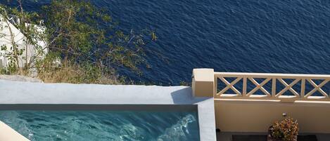 A pool with clear blue water, a white railing, and a view of the ocean.