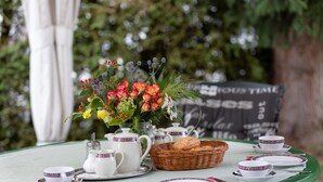 A table set with white teacups, saucers, a teapot, and a basket of bread. - Hotel Garni Silberdistel (Hinterzarten)