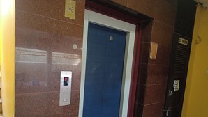 An elevator with a digital display, a blue door, and a sign indicating an EB room. - Green Tree Hotel (Chennai)