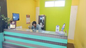 A reception desk with a glass top, a framed certificate, a calendar, and a sign for PhonePe. - Green Tree Hotel (Chennai)