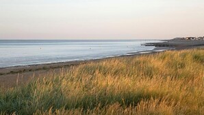 A beach with a grassy foreground and a calm sea.