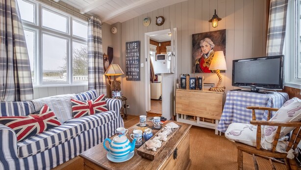 A cozy living room with a sofa, a coffee table with tea set, a television, and a painting on the wall.