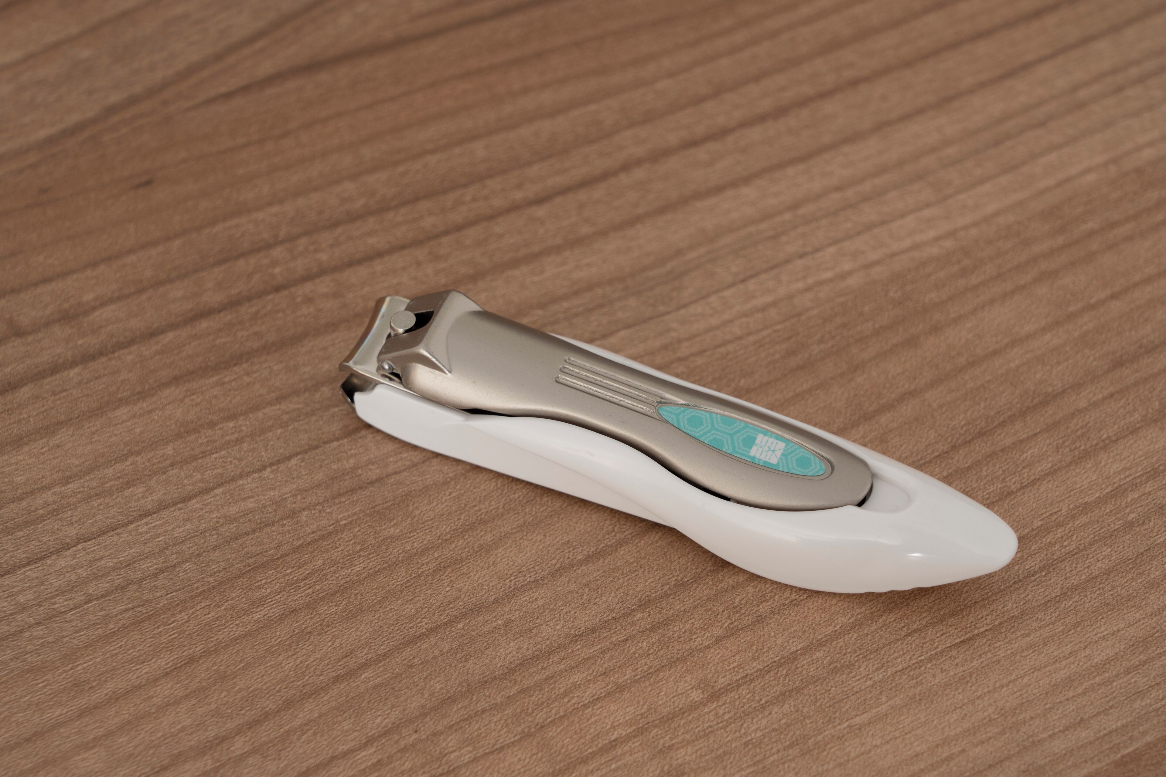 A portable electric nail clipper on a wooden surface.