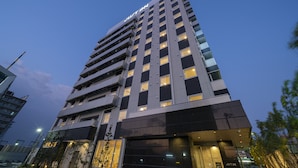 Un hotel de gran altura con numerosos pisos, ventanas amplias y una entrada destacada en la base.