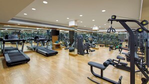 A gym with treadmills, weight machines, and mirrors on the walls. - Sobit Sarovar Portico Goa (Canacona)