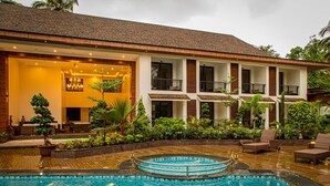A hotel with a swimming pool, outdoor seating, and a well-maintained garden. - Sobit Sarovar Portico Goa (Canacona)