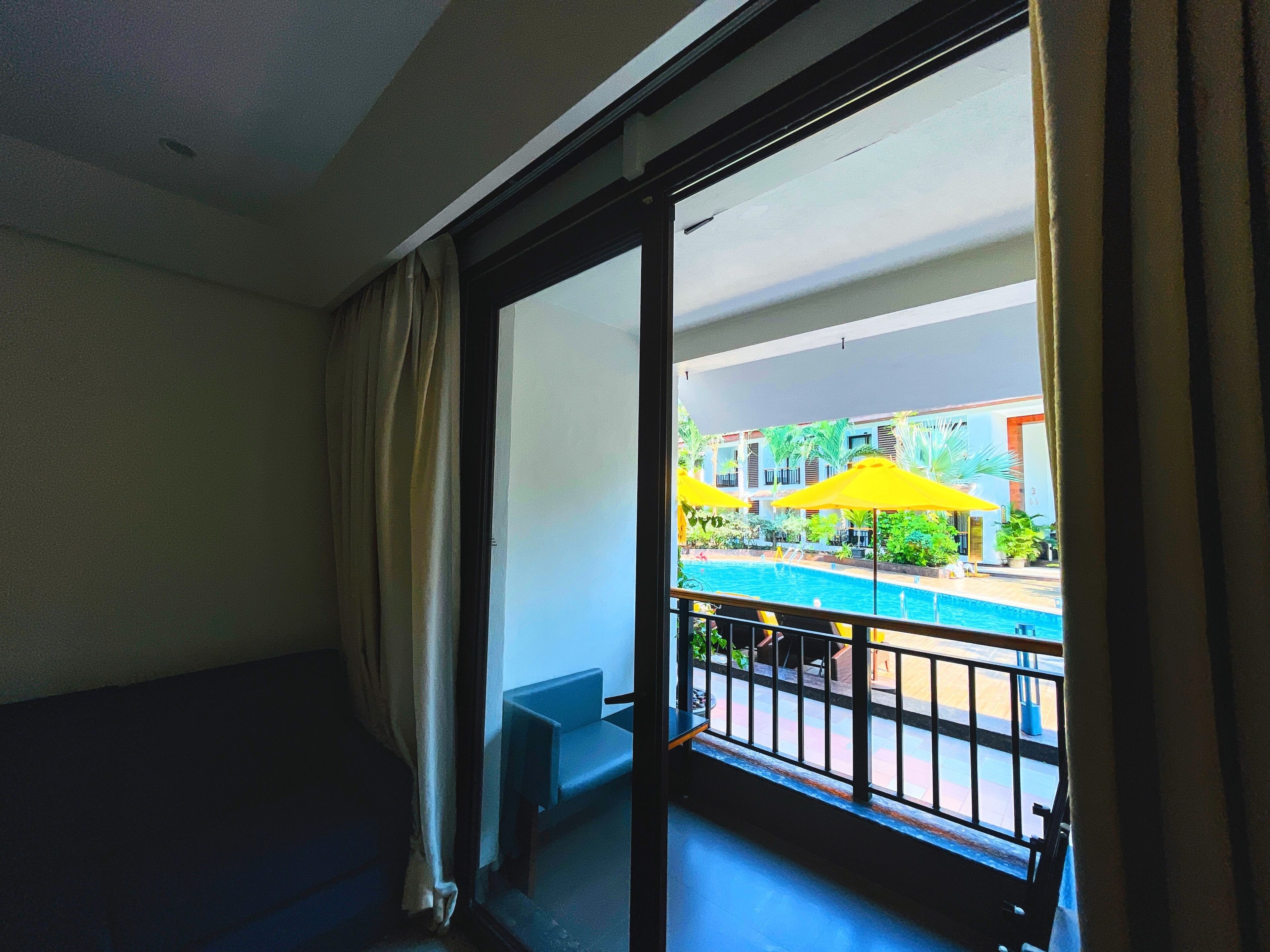Una stanza con vista su una piscina, un balcone con ringhiera e una finestra con tende.